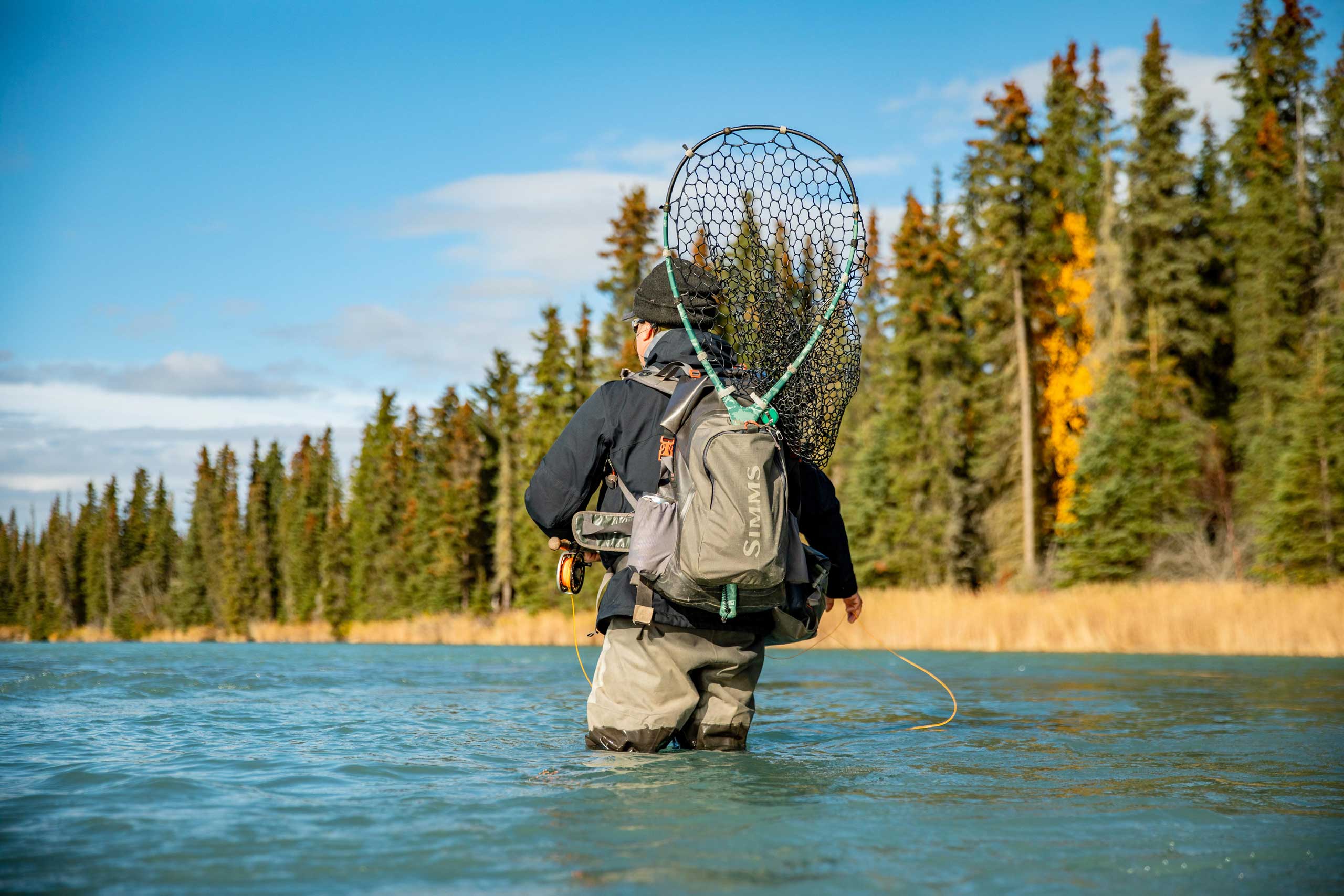 An angler wading a Kenai Peninsula river with net in hand